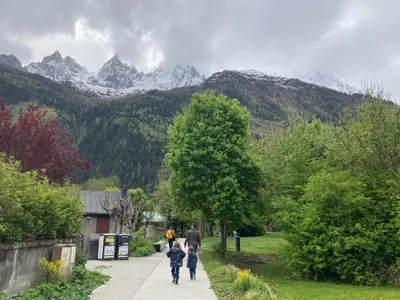 a group of people walking down a sidewalk with mountains in the background at Abeille de Chamonix in Chamonix-Mont-Blanc