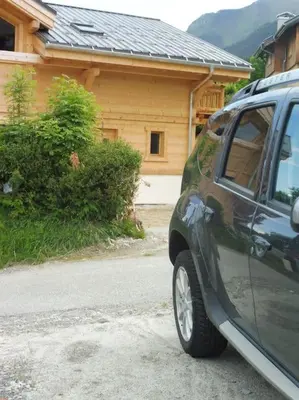 a green suv parked in front of a house at demi chalet Les Contamines Le Virolet in Les Contamines-Montjoie