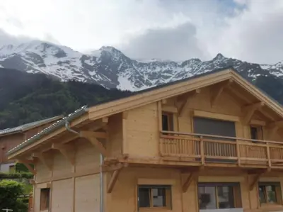 a log cabin with snow covered mountains in the background at demi chalet Les Contamines Le Virolet in Les Contamines-Montjoie