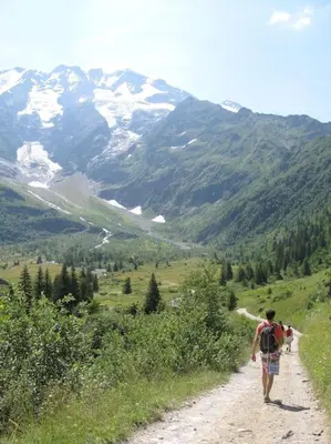 a man walking down a dirt road on a mountain at demi chalet Les Contamines Le Virolet in Les Contamines-Montjoie