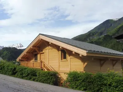 a wooden house with a roof with a mountain at demi chalet Les Contamines Le Virolet in Les Contamines-Montjoie