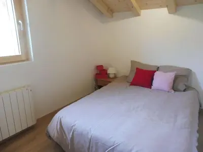 a bedroom with a bed with red and purple pillows at demi chalet Les Contamines Le Virolet in Les Contamines-Montjoie