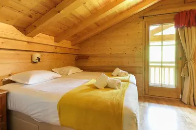 a bedroom with two beds in a log cabin at Maison Neuve - Ski aux pieds - Vue Mt-Blanc in Les Houches