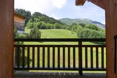 a porch with a view of a green field and mountains at Maison Neuve - Ski aux pieds - Vue Mt-Blanc in Les Houches