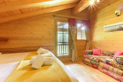 a log cabin bedroom with two beds and a couch at Maison Neuve - Ski aux pieds - Vue Mt-Blanc in Les Houches