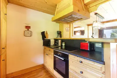 a kitchen with wooden cabinets and a black counter top at Maison Neuve - Ski aux pieds - Vue Mt-Blanc in Les Houches