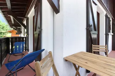 a blue chair and a wooden table on a balcony at La Griaz - Chaleureux et cosy -Vue sur les montagnes - grand balcon in Les Houches