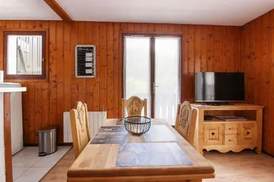 a dining room with a table and a television at La Griaz - Chaleureux et cosy -Vue sur les montagnes - grand balcon in Les Houches