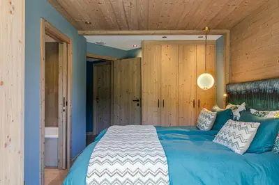 a bedroom with a blue bed and wooden walls at Rochebrune - Appartement de luxe in Megève