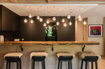 a kitchen with a bar with stools and lights at Rochebrune - Appartement de luxe in Megève