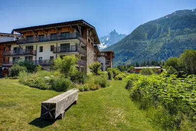 a bench sitting in the grass in front of a building at Apartment Chéserys, Alpes Travel, Les Praz Sleeps 2-4 in Chamonix-Mont-Blanc