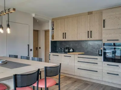 a kitchen with wooden cabinets and a table with chairs at Confortable 3 pièces à Megève avec Wi-Fi et garage à skis - FR-1-453-306 in Megève