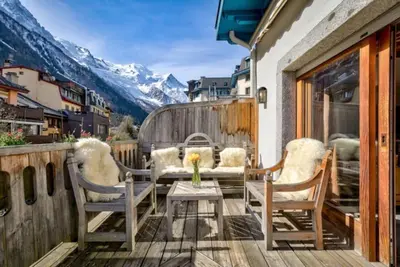 a balcony with a table and chairs and mountains at Spacious 3-bed in the heart of Chamonix with sauna in Chamonix-Mont-Blanc