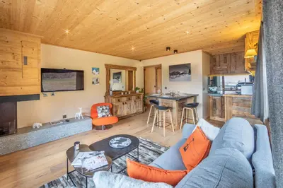 a living room with a blue couch and a kitchen at Les Corneilles - Appartement in Megève