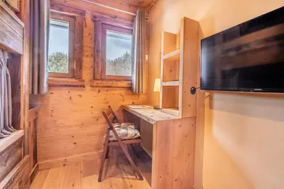 a room with a desk and a television in a log cabin at Les Corneilles - Appartement in Megève