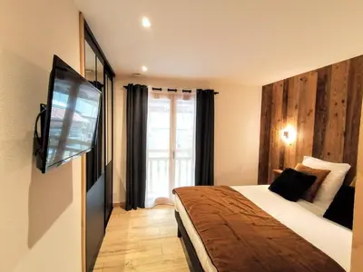 a hotel room with a bed and a flat screen tv at Chez Lucienne, jacuzzi et sauna in Samoëns