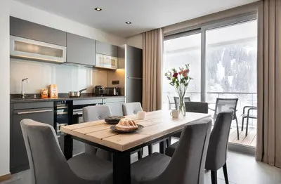 a kitchen and dining room with a wooden table and chairs at MGM Hôtels & Résidences - Résidence Alhéna in Flaine