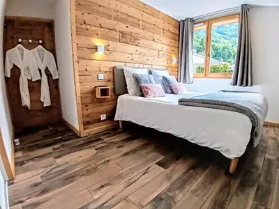 a bedroom with a bed and a wooden wall at Chez Léon Jacuzzi et sauna in Samoëns