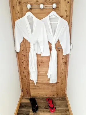 two white shirts hanging on a wooden wall with red shoes at Chez Léon Jacuzzi et sauna in Samoëns