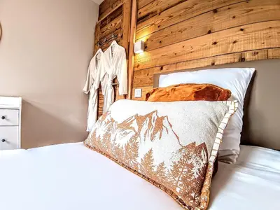 two beds in a bedroom with a wooden wall at Chez Léon Jacuzzi et sauna in Samoëns