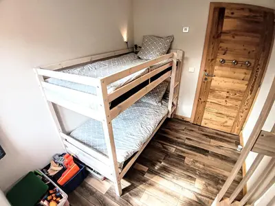 a bunk bed room with two bunk beds and a door at Chez Léon Jacuzzi et sauna in Samoëns