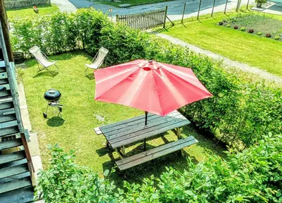 a red umbrella sitting on a picnic table with a bench at Chez Léon Jacuzzi et sauna in Samoëns