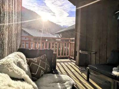 a balcony with a couch and a view of a mountain at Chez Léon Jacuzzi et sauna in Samoëns