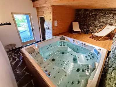 a large bath tub in a room with a stone wall at Chez Léon Jacuzzi et sauna in Samoëns