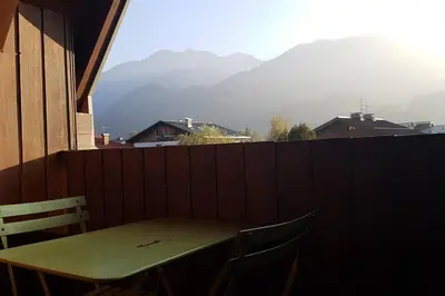 a table and chairs on a balcony with a view of mountains at Appartement Les Dents Blanches - Samöens Centre in Samoëns