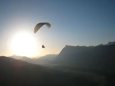 a person riding a parachute in front of the sun at Appartement Les Dents Blanches - Samöens Centre in Samoëns