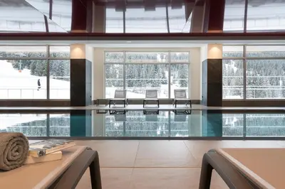 a swimming pool with chairs in a building at MGM Hôtels & Résidences - Hôtel Alhéna in Flaine
