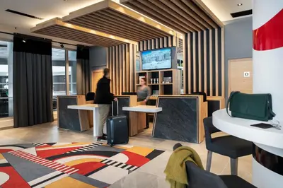 a lobby with two people standing at a counter at MGM Hôtels & Résidences - Hôtel Alhéna in Flaine