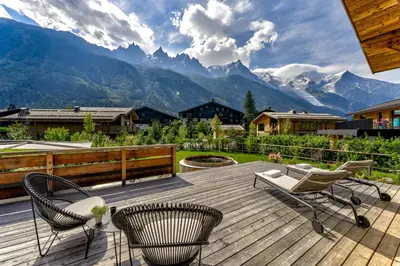 a deck with chairs and a view of mountains at Chalet Trois Soeurs in Chamonix-Mont-Blanc