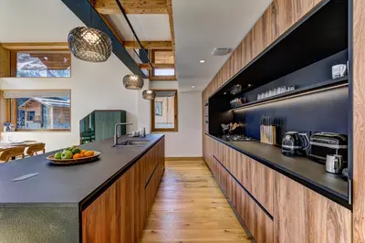 a kitchen with black countertops and wooden cabinets at Chalet Trois Soeurs in Chamonix-Mont-Blanc