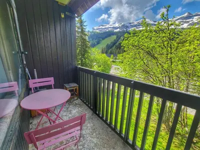 a balcony with a pink table and chairs and mountains at Appart. 38m² pour 6 pers, balcon sud, pied des pistes - FR-1-687-115 in Arâches-la-Frasse