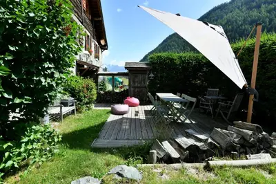 a patio with a table and a white umbrella at Le Vallorcin, chalet le Sizeray vallée de Chamonix & Mont Blanc - by ImmoConciergerie in Vallorcine