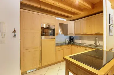 a kitchen with wooden cabinets and a stove top oven at Le Quatre - 75m2 Charmant Duplex - Central - 8-10 pax 3ch in Saint-Gervais-les-Bains
