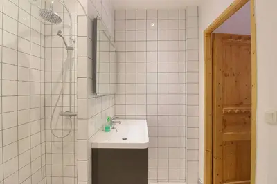 a white tiled bathroom with a sink and a shower at Le Quatre - 75m2 Charmant Duplex - Central - 8-10 pax 3ch in Saint-Gervais-les-Bains