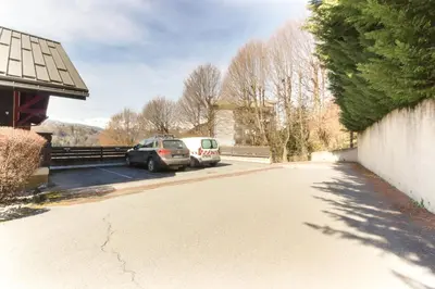 two cars parked in a parking lot next to a building at Le Quatre - 75m2 Charmant Duplex - Central - 8-10 pax 3ch in Saint-Gervais-les-Bains