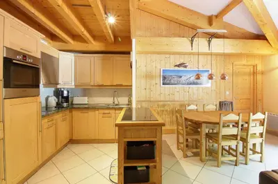 a kitchen with wooden cabinets and a wooden table at Le Quatre - 75m2 Charmant Duplex - Central - 8-10 pax 3ch in Saint-Gervais-les-Bains