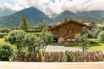 a house in a field with mountains in the background at Appartement Yoga - Vues Chaîne du Mont-Blanc - Calme - Espace Yoga Spacieux in Les Houches