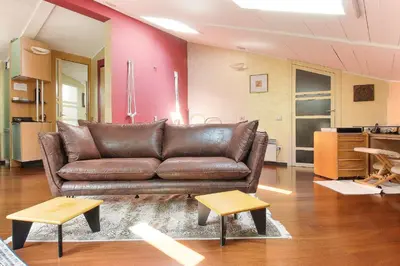 a living room with a brown leather couch and two tables at Appartement Yoga - Vues Chaîne du Mont-Blanc - Calme - Espace Yoga Spacieux in Les Houches