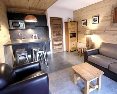 a living room with a couch and a kitchen at Studio avec coin montagne au pied des pistes in Megève