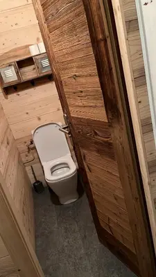 a bathroom with a toilet and a wooden door at Studio avec coin montagne au pied des pistes in Megève