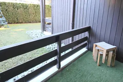 a wooden bench next to a fence with a window at Studio avec coin montagne au pied des pistes in Megève