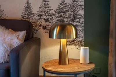 a gold lamp on a table next to a bed at Nid douillet au cœur de Megeve in Megève