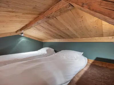 a bed in a room with a wooden ceiling at Nid douillet au cœur de Megeve in Megève
