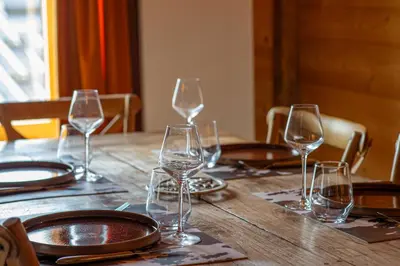 a wooden table with wine glasses and plates on it at Nid douillet au cœur de Megeve in Megève