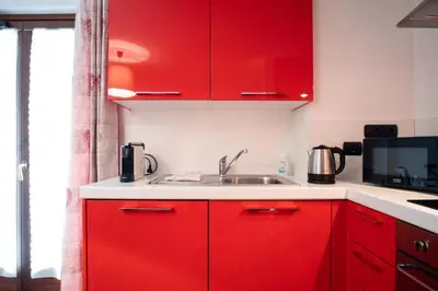 a kitchen with red cabinets and a sink at Les Alpes 3 - Central - Rénové - Vue sur la chaîne du Mont-Blanc in Chamonix-Mont-Blanc