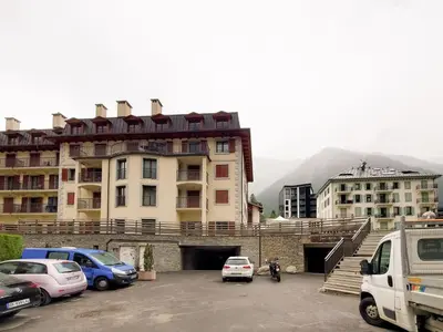 a parking lot with cars parked in front of a building at Les Alpes 3 - Central - Rénové - Vue sur la chaîne du Mont-Blanc in Chamonix-Mont-Blanc